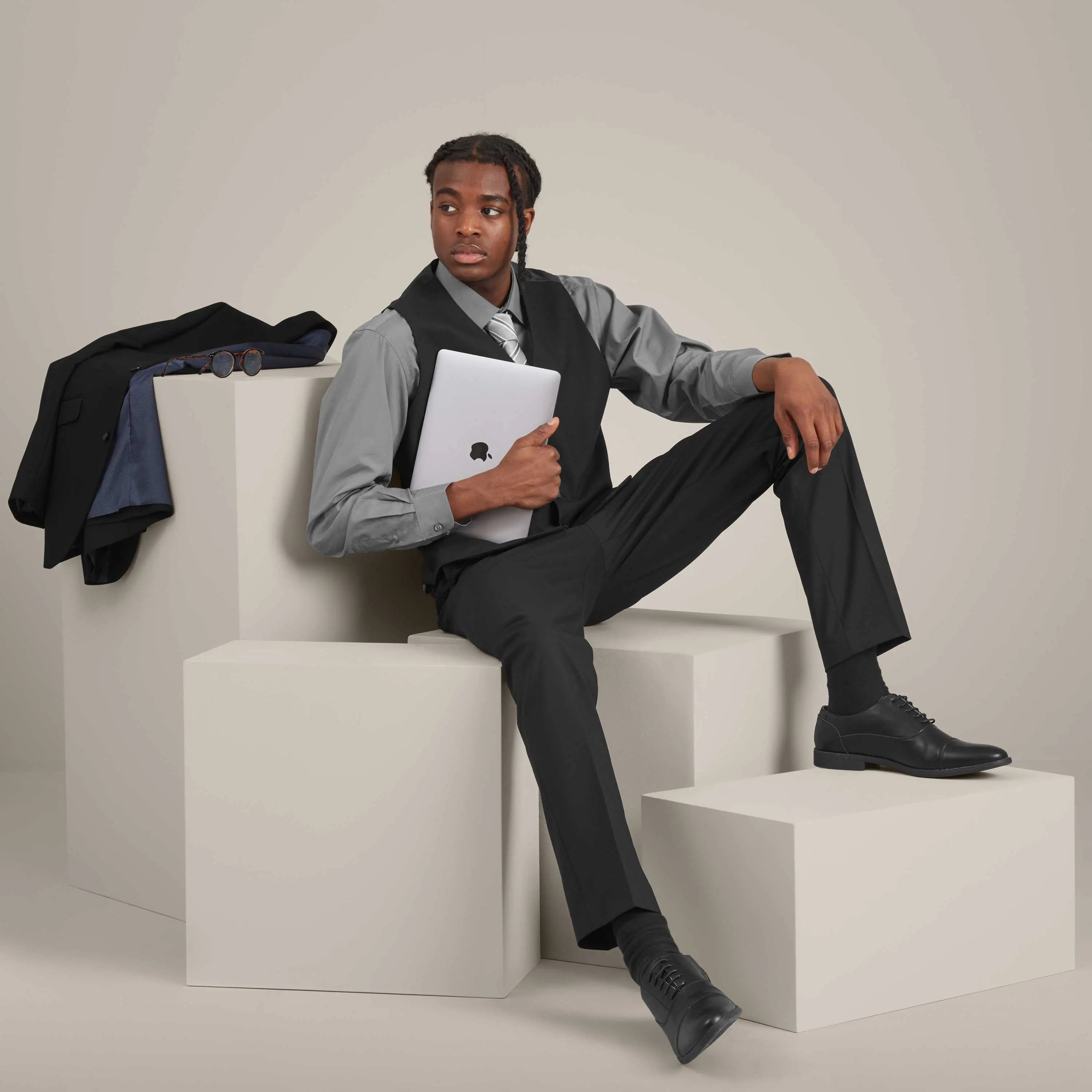 Model wearing Work Uniform Company menswear, holding a MacBook, with a white background