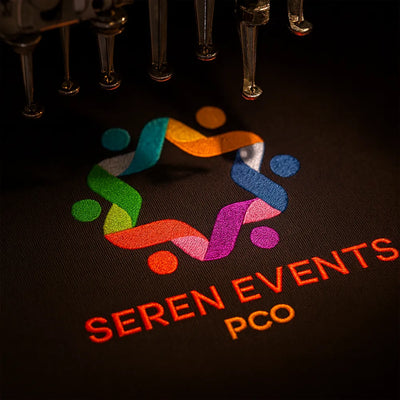 Embroidered logo and text on a dark fabric with colourful design