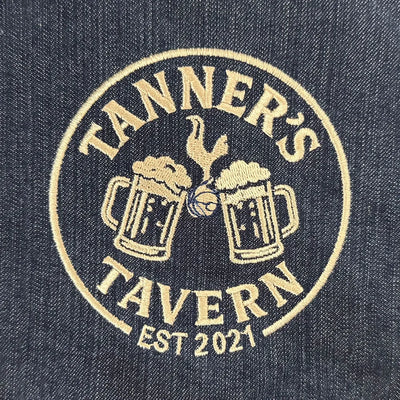 Embroidered logo of 'Tanner's Tavern' on denim fabric