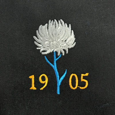 Embroidered design of a flower with the numbers '1905' on a black background