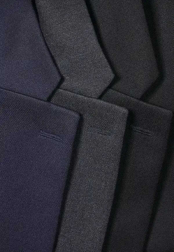 A close-up of folded Concept Collection suit jacket lapels in dark navy, charcoal gray, and black, showing the fine twill fabric texture.