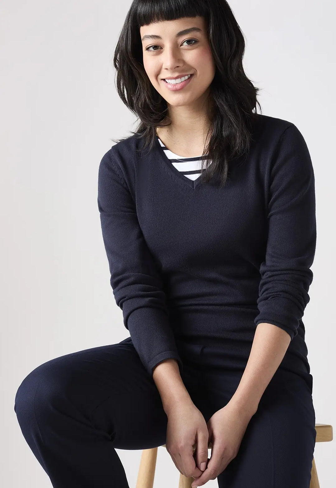 Lifestyle photo of model wearing the Henbury Women's 12 Gauge V Neck Jumper in Navy.