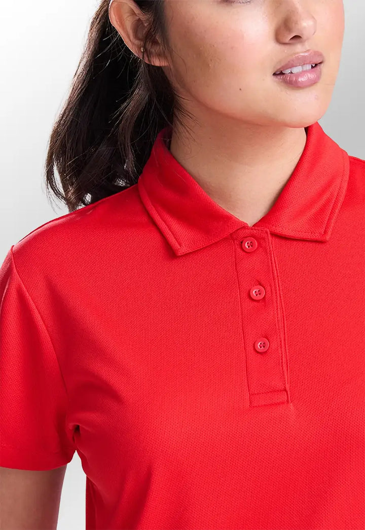 Closeup view of model wearing the AWDis Ladies Cool Polo JC045 in Fire Red.