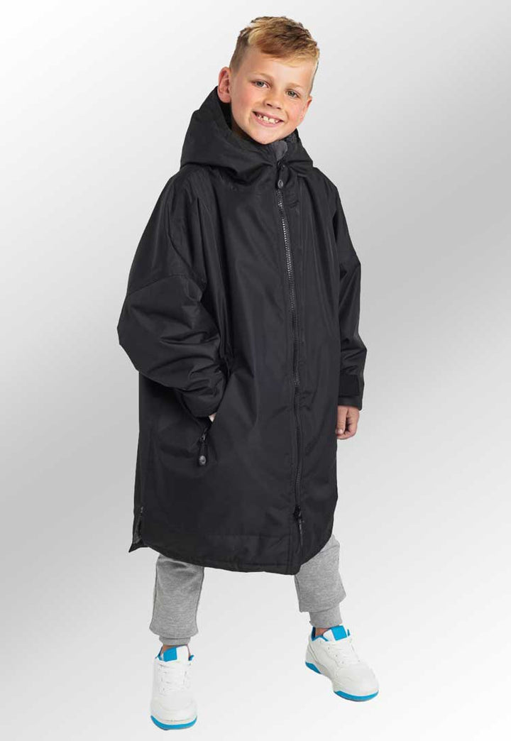 Model wearing Kids TriDri® All-Seasons Waterproof Changing Robe TR80B in black/charcoal