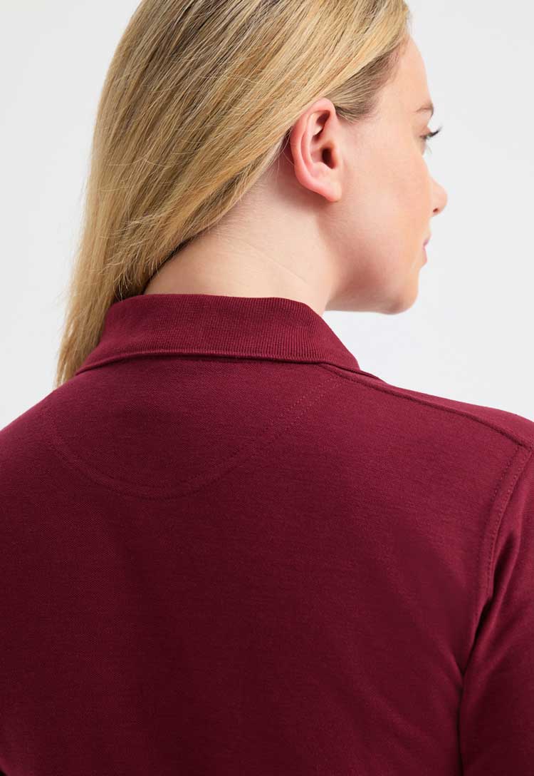 close up back view of model wearing uneek Ladies Classic Polo Shirt in maroon