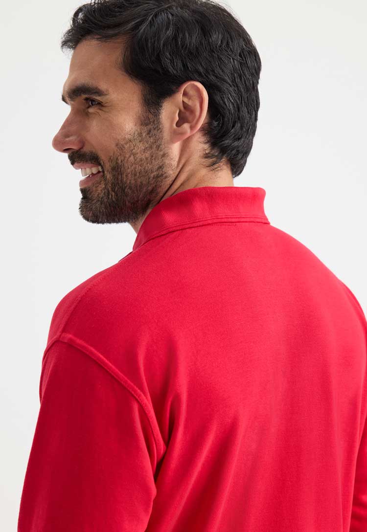 close up back view of model wearing uneek long sleeve polo in red