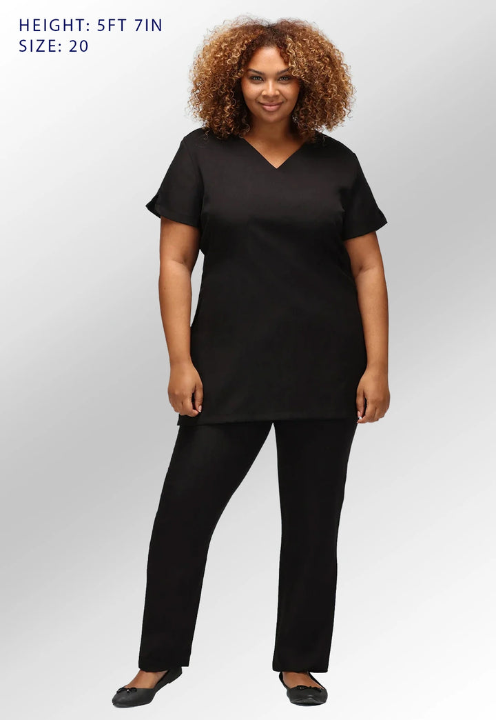Fully body view of model wearing the La Beeby Black Nina V Neck Salon Tunic with Pockets. Height: 5ft 7in. Size: 20.
