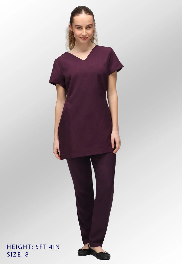 Fully body view of model wearing the La Beeby Plum Nina V Neck Salon Tunic with Pockets. Height: 5ft 4in. Size: 8.
