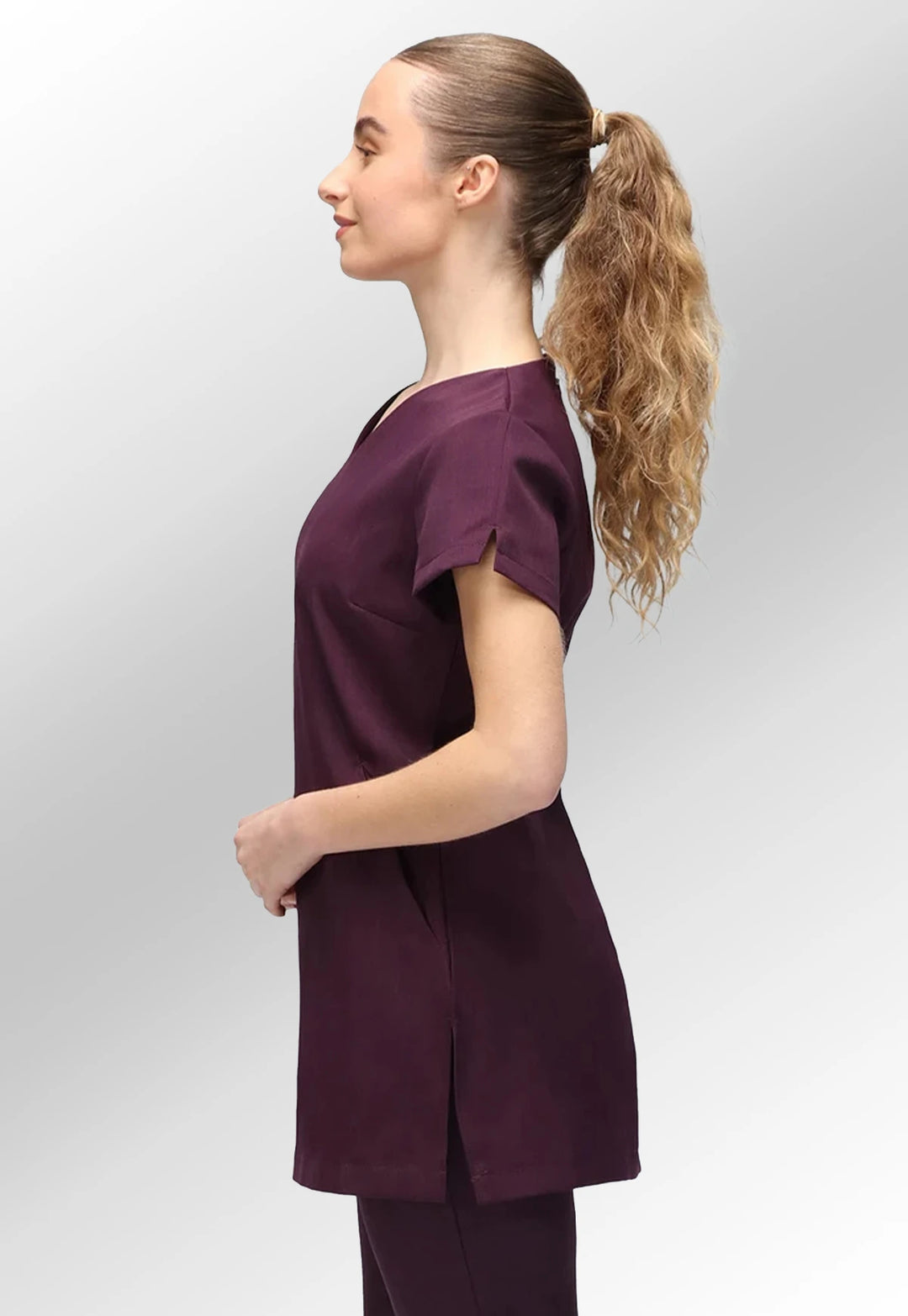 Side view of model wearing the La Beeby Plum Nina V Neck Salon Tunic with Pockets.