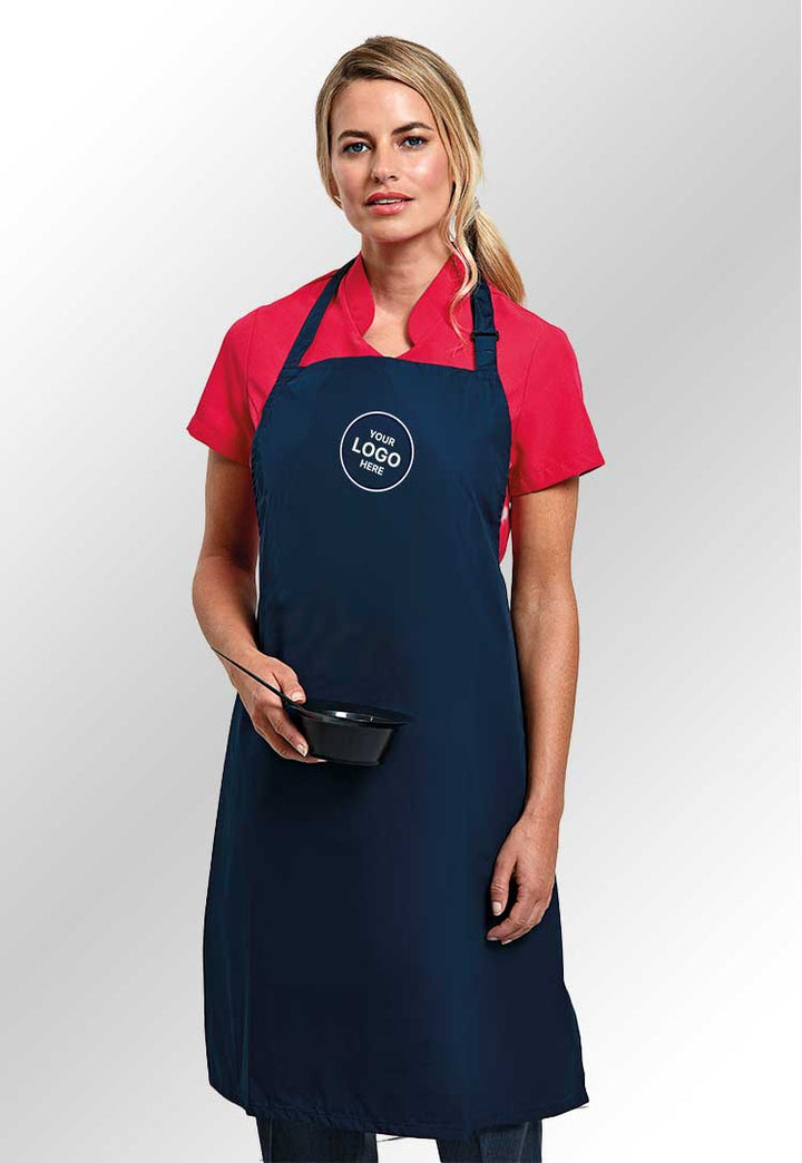 Model wearing a PR115 Waterproof bib apron in Navy with a 'Your Logo Here' sign on the chest