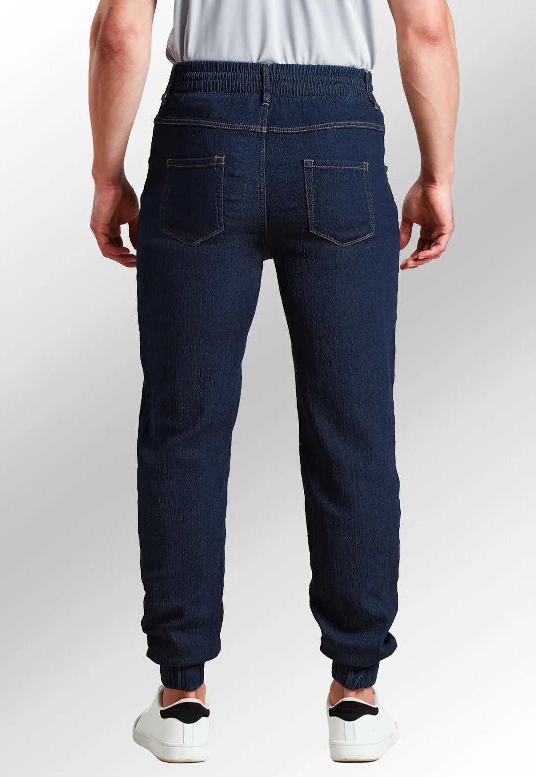 Rear view of model wearing the Premier Workwear Chef's Artisan Jogger Bottoms PR556 in Indigo Denim.