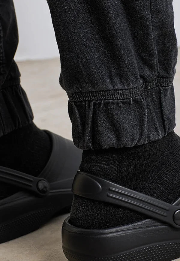 Ankle close-up of model wearing the Chef's Artisan Jogger Bottoms PR556 in Black Denim.