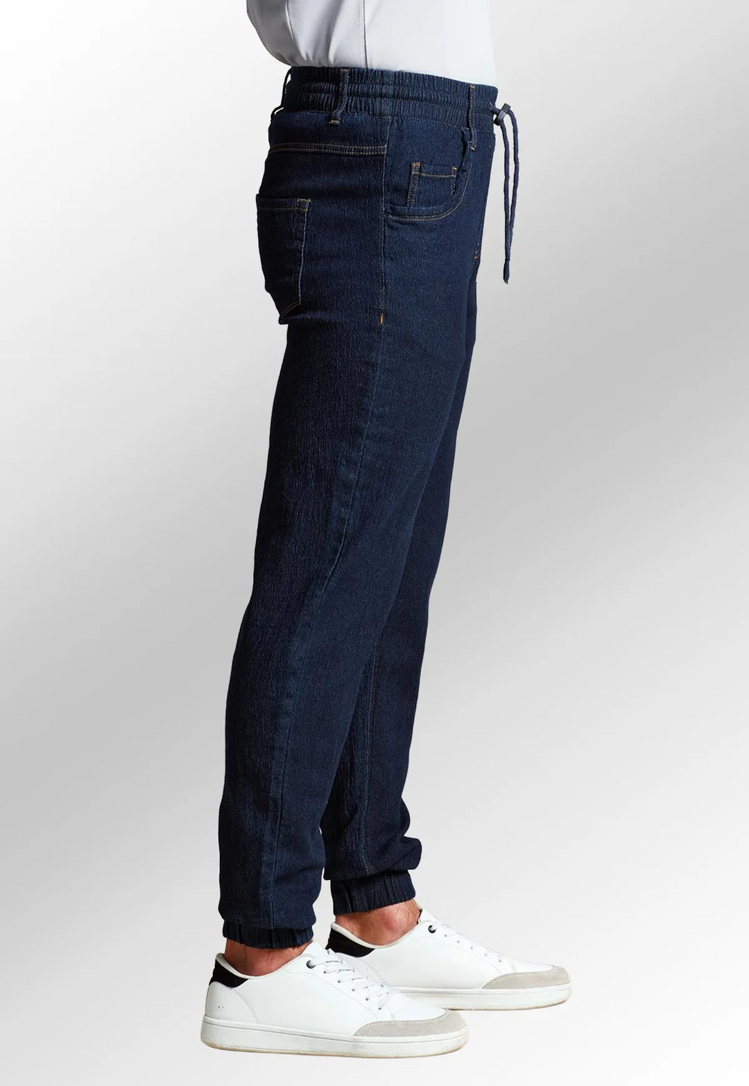 Side view of model wearing the Premier Workwear Chef's Artisan Jogger Bottoms PR556 in Indigo Denim.