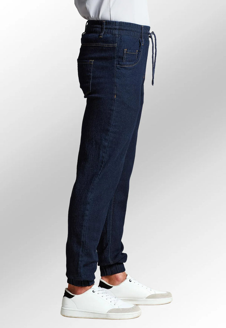 Side view of model wearing the Premier Workwear Chef's Artisan Jogger Bottoms PR556 in Indigo Denim.