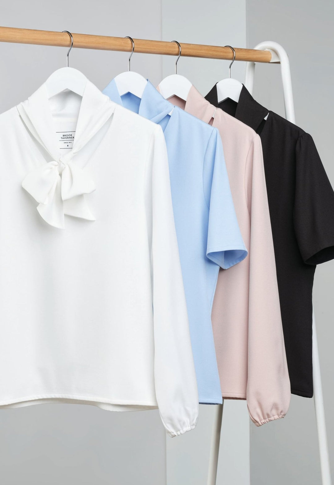 Collection of Andria Pussy Bow Blouses 2368 in White, Sky Blue, Nude and Black Hanging on Rack